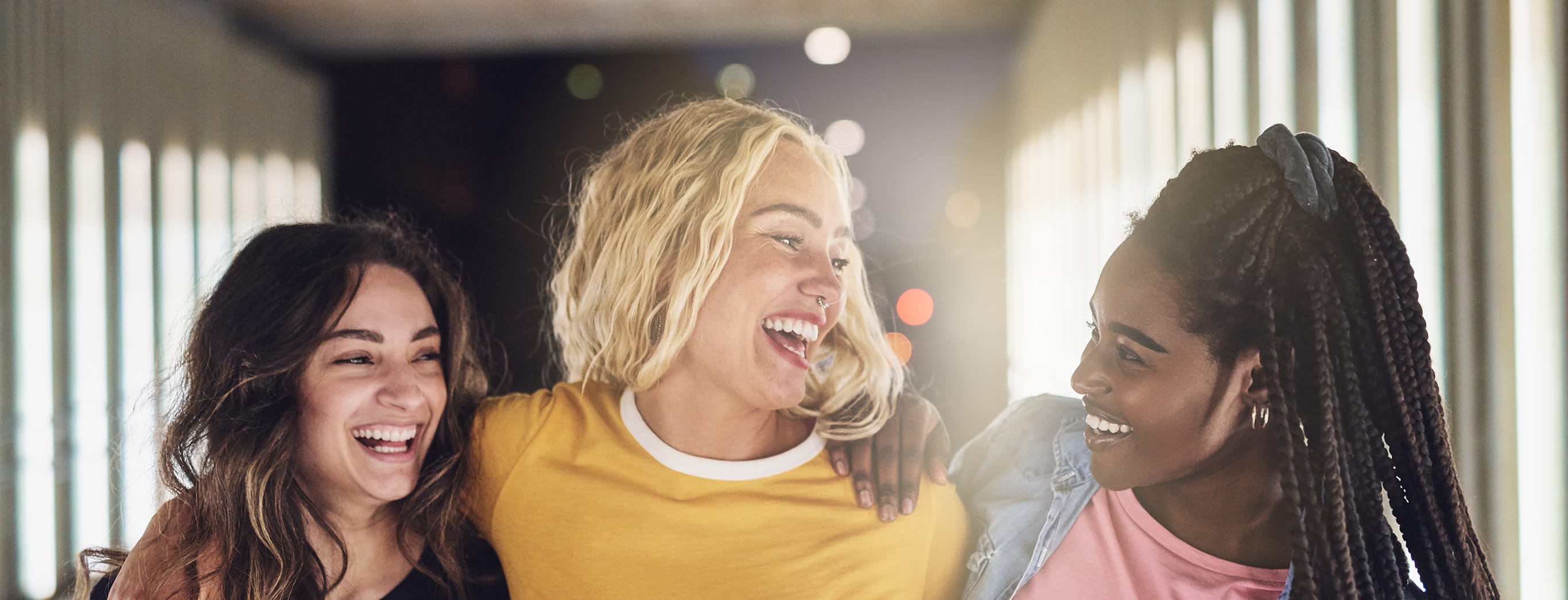 Three young women laughing and smiling in an urban setting