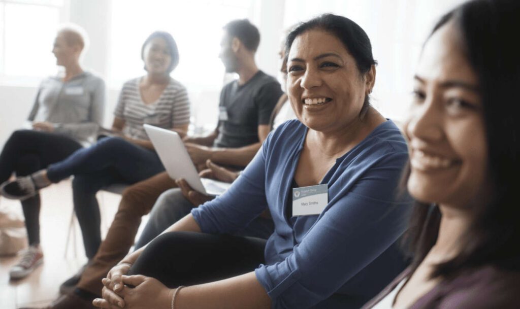 Community meeting with members smiling and chatting